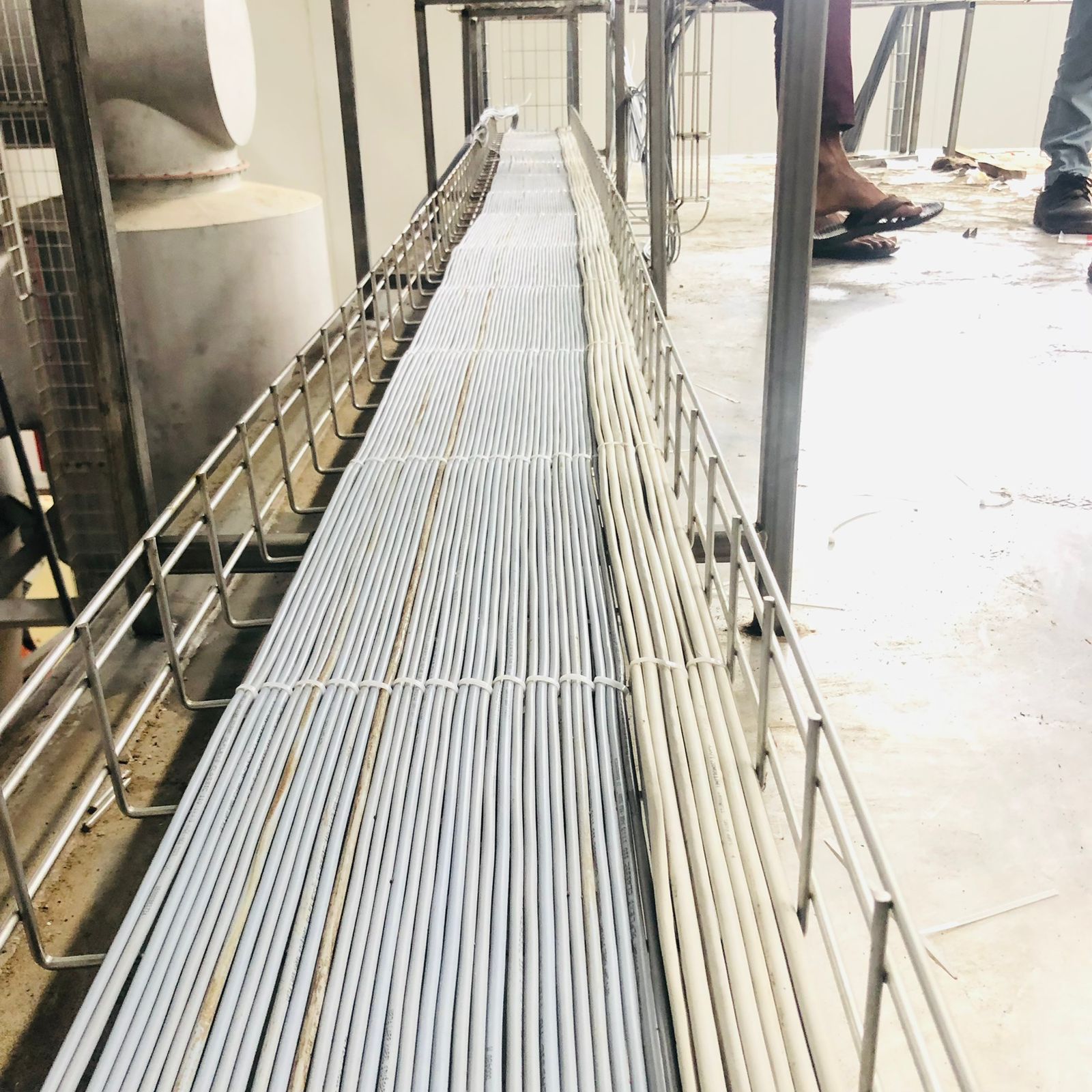 Close-up of multiple bundles of electrical wires neatly laid in a metal mesh cable tray.