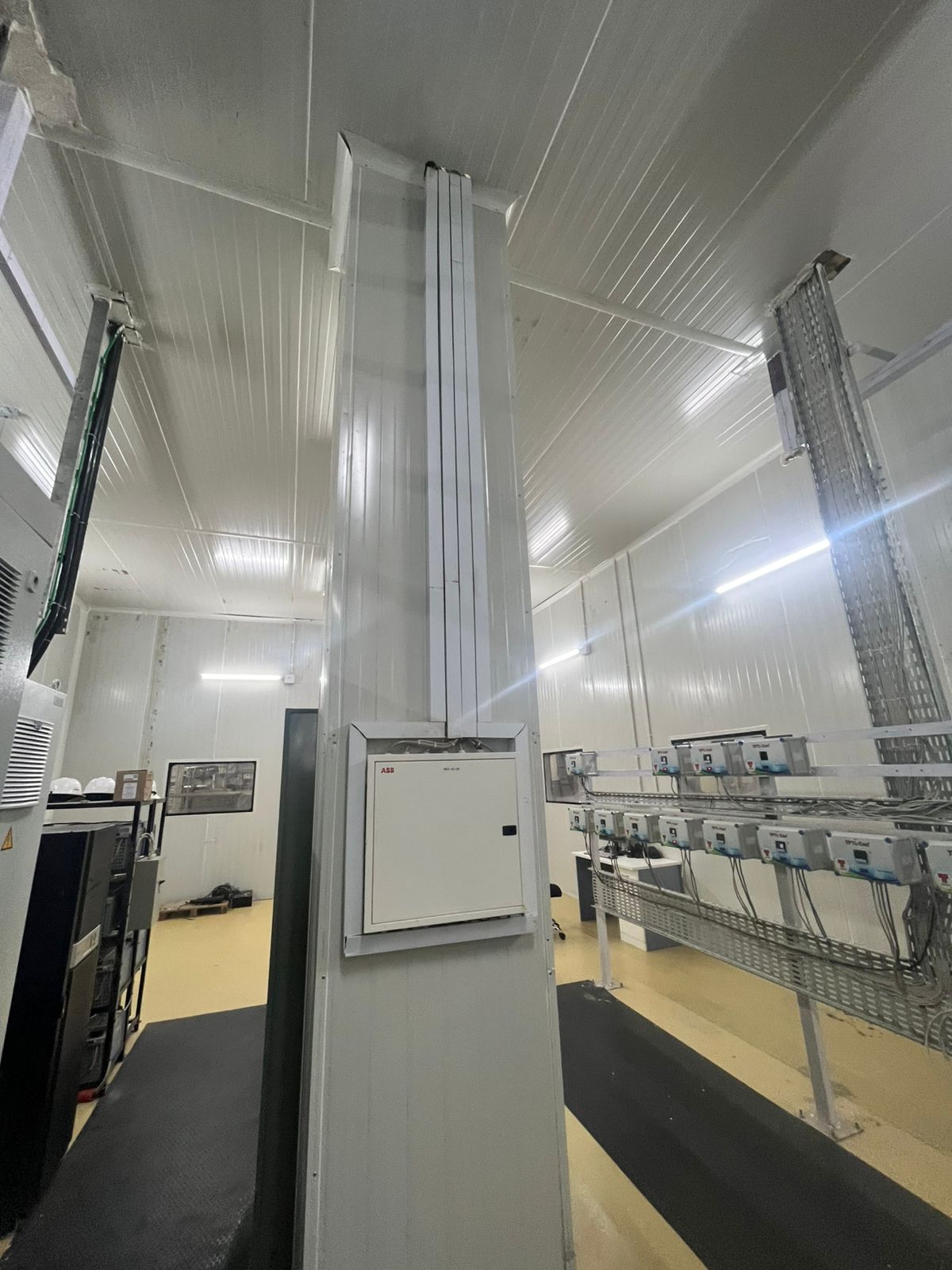 Corner of a modern, clean room with a tall white column and an "ABB" electrical panel box on the wall.